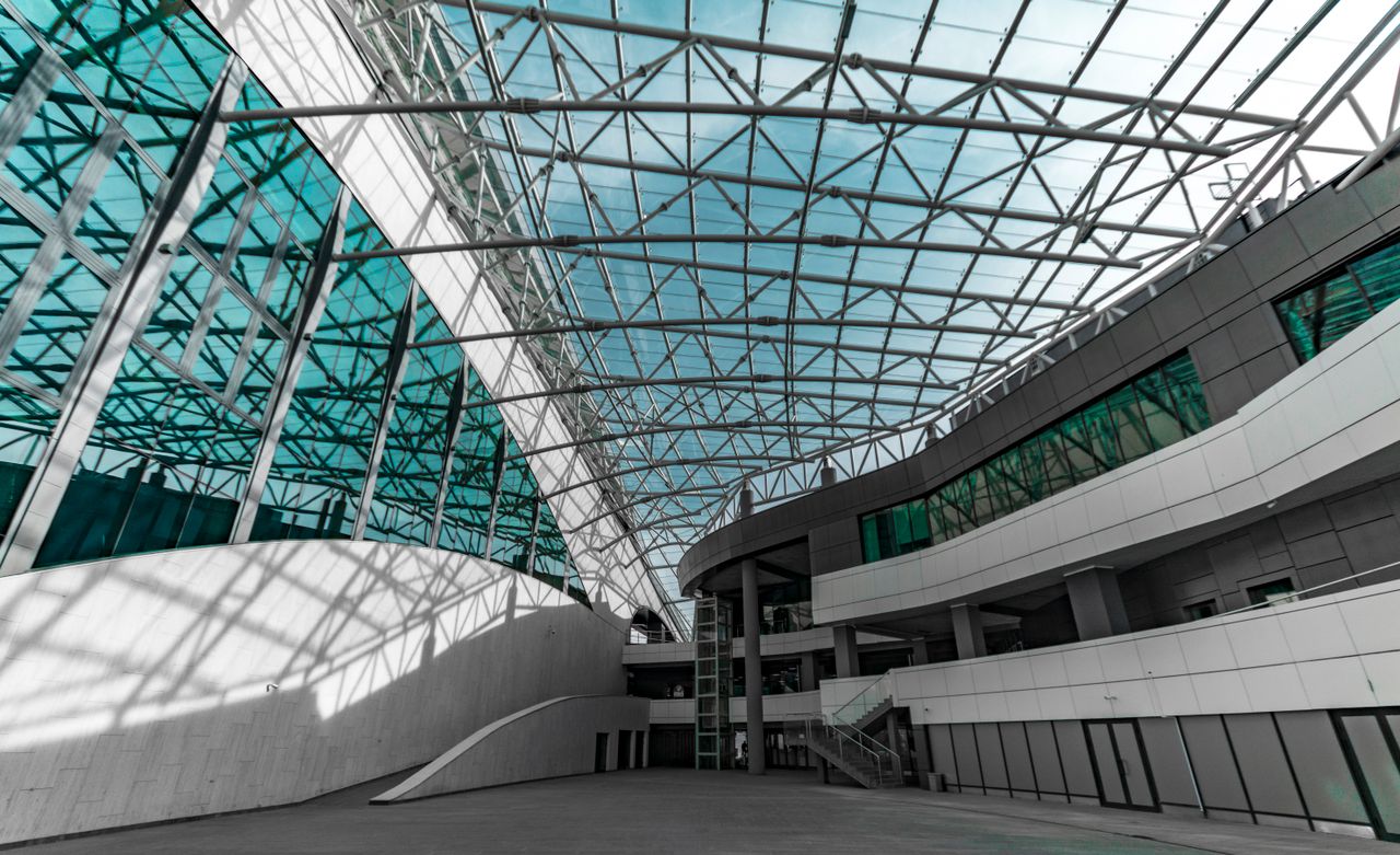 services-01 Modern architectural space with high glass ceilings and steel structures.